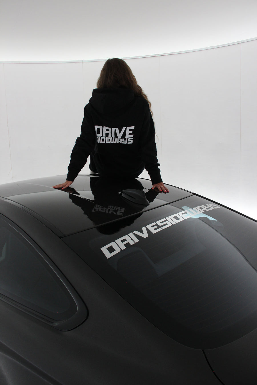 Drive Sideways Hoodie päällä, malli istuu auton katolla
